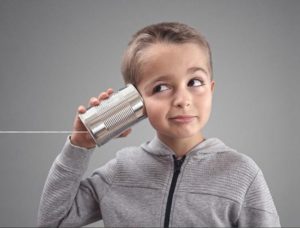 photo of child holding a can on a string to his ear